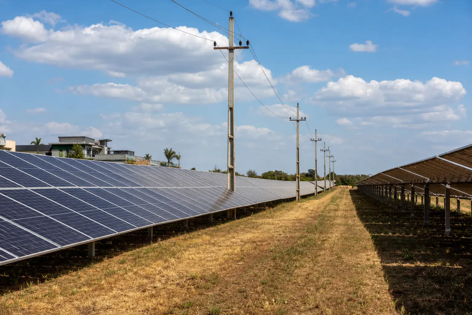 Usina solar com fileiras de painéis e linha de distribuição levando a energia para a rede